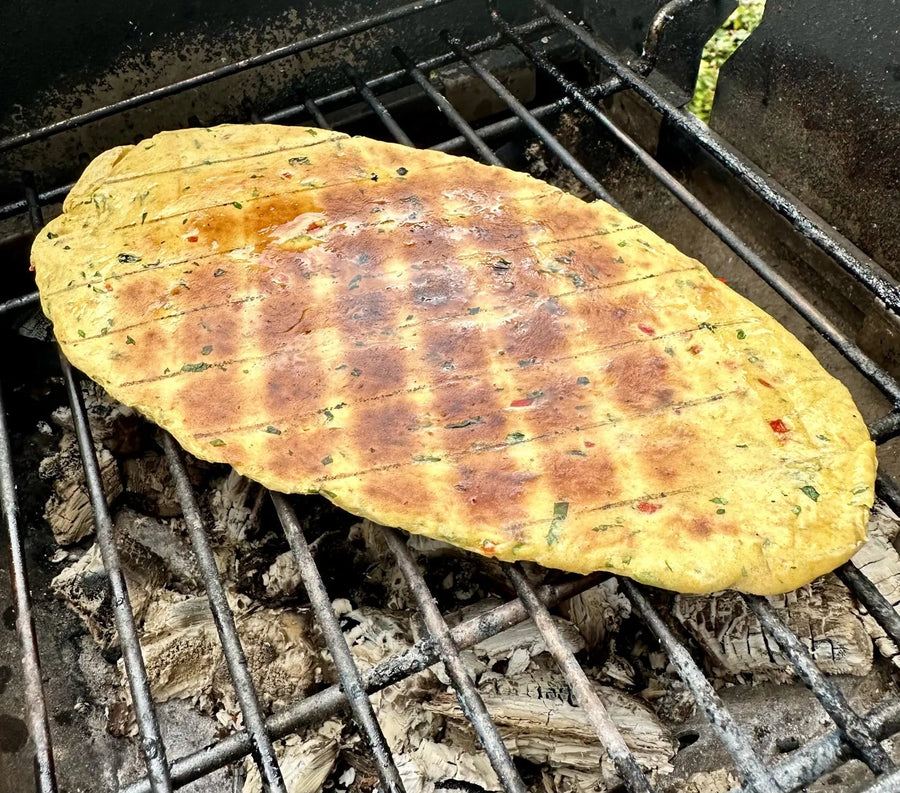 A herb flatbread on the grill bars over hot coals